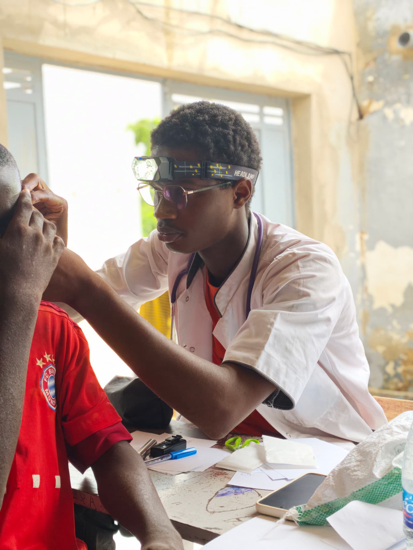 Un soignant examine un patient avec une lampe frontale